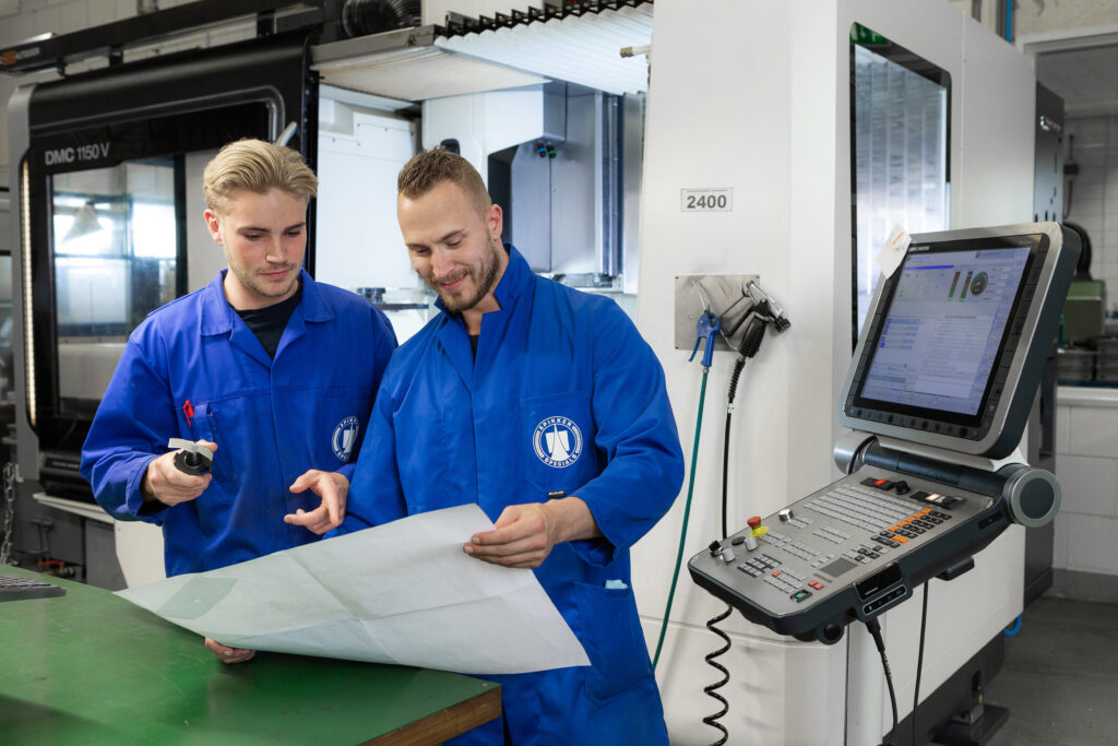 Medewerkers (productie) Spikker Specials bekijken een ontwerp van een machinecomponent dat zij gaan produceren